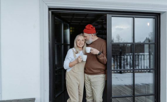 man and woman standing by the door holding mugs