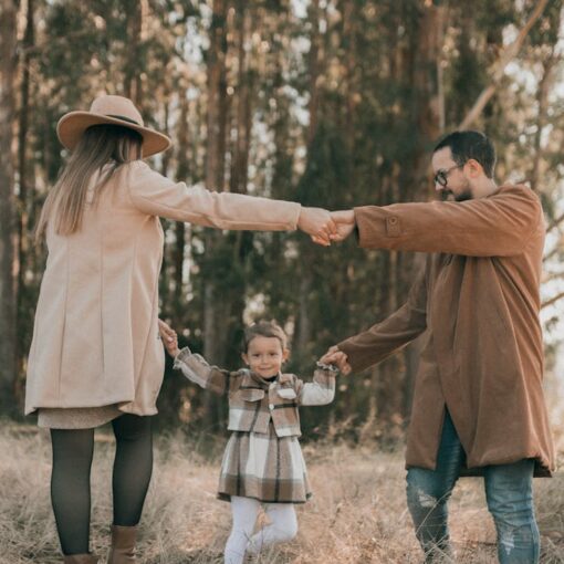a family with a little daughter dancing in a forest in autumn
